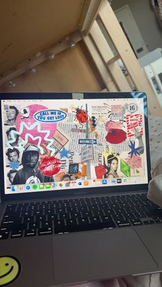 an open laptop computer sitting on top of a bed covered in stickers and paper