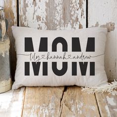 a pillow with the word mom on it sitting next to two jars and a plant