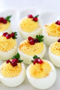 deviled eggs with cranberries and mustard are arranged on a white platter