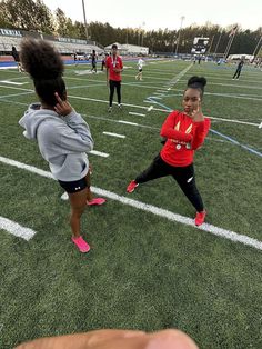 two girls on a field playing with a frisbee and another girl in the background