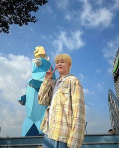 a boy standing in front of a blue and yellow sculpture with a bird on it's head