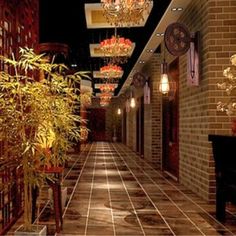 a long hallway with chandeliers hanging from the ceiling and potted plants on either side