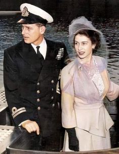 a man and woman in dress clothes standing next to each other on a boat with water behind them