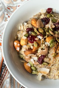 a bowl filled with oatmeal topped with nuts and dried cranberries