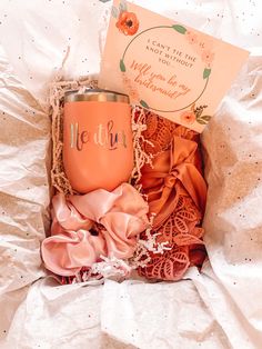 an orange wine cup sitting inside of a box next to a greeting card and ribbon