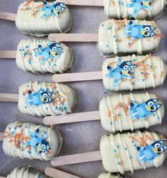 several marshmallows with frosting and cartoon characters are arranged on wooden skewers