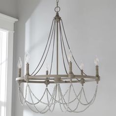 a chandelier hanging from the ceiling in a room with white walls and windows