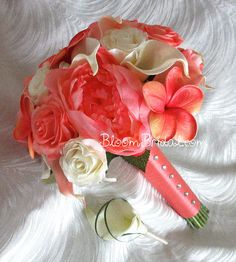 a bridal bouquet with pink and white flowers on a white cloth covered bed sheet