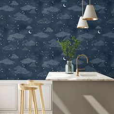 a kitchen with blue wallpaper and white counter tops, two stools in front of the sink