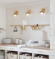 an organized laundry room with white cabinets and gold fixtures, including hanging baskets on the wall