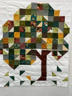 a quilted wall hanging with an abstract tree design on the front and back side