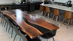 a large wooden table sitting in the middle of a kitchen next to bar stools