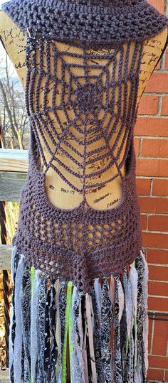 a mannequin is covered in crochet and yarns, with an intricate spider web design on the back