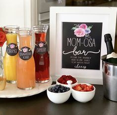 a table topped with drinks and fruit next to a chalkboard that says mom - o - clock