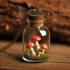 a glass jar filled with tiny mushrooms sitting on top of a wooden table next to a chain