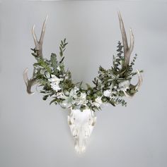 the antlers are adorned with white flowers and greenery