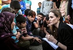 a woman sitting on the ground surrounded by other people and looking at something in her hand