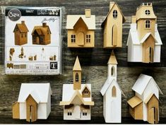 several wooden houses are displayed on a table with the package next to them and one is empty