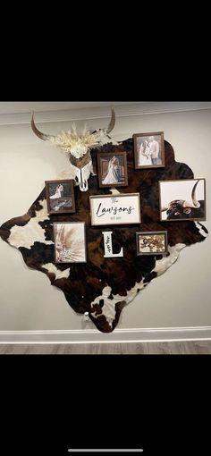 a cow skin wall hanging on the side of a wall with pictures and photos attached to it