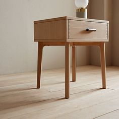 an end table with a lamp on top of it next to a window in a room