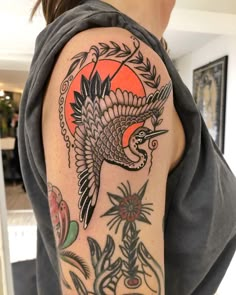 a woman's arm with a bird and flowers tattoo design on the left shoulder