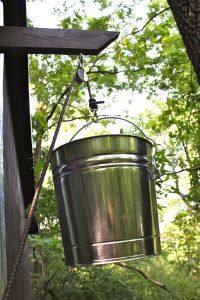 a metal bucket hanging from a tree branch