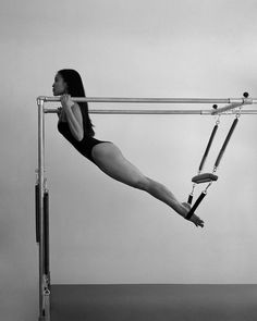 a woman in a black leotard is on the pole and has one leg up