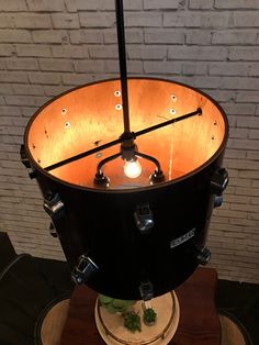 a large black drum on top of a wooden table next to a white brick wall