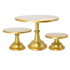 three gold pedestals with white tops and one has a small round table on top