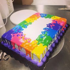 there is a cake that looks like it has been painted with rainbows and white icing