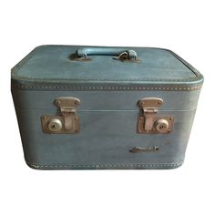 an old blue suitcase with two handles and latches on the handle, sitting against a white background