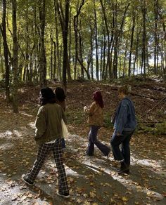 three people walking in the woods with leaves on the ground