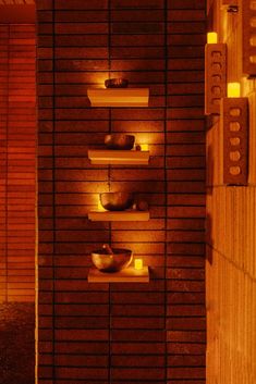 a sauna room with candles and bowls on the shelves in front of it at night