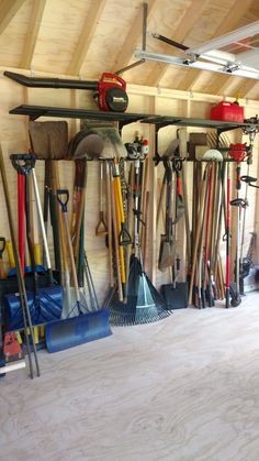 a garage filled with lots of different types of shovels and rakes hanging from the ceiling