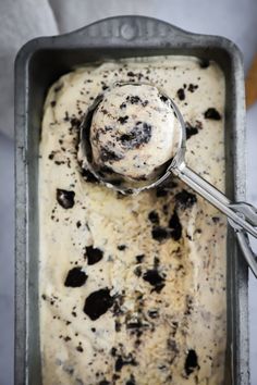 a scoop of ice cream in a metal pan with black and white sprinkles