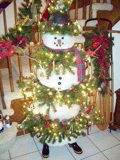 a christmas tree with snowmen on it in the middle of a room filled with stairs