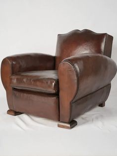 a brown leather chair sitting on top of a white floor