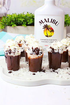 there are cupcakes with chocolate frosting and whipped cream on the top, next to a bottle of malbu