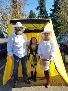 three people dressed up in bee costumes standing next to a yellow tent with the door open