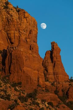 the moon is setting behind some red rocks