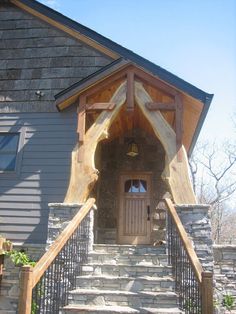 a house with stone steps leading up to the front door and entry way that has a wooden railing on both sides