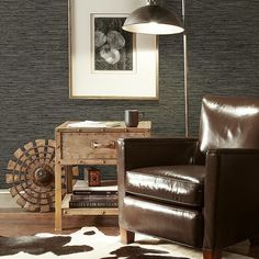 a brown chair sitting in front of a lamp on top of a wooden table next to a cowhide rug