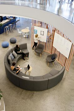 a circular couch sitting in the middle of a room with people working on laptops