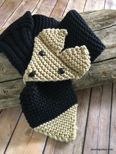 a crocheted scarf is laying on a wooden surface with a piece of wood in the background