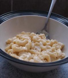 a bowl filled with macaroni and cheese on top of a marble countertop