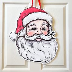 a christmas ornament hanging on a door with a santa clause hat and beard