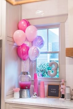 pink and purple balloons are on the window sill in front of a number 3 sign