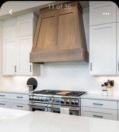 a kitchen with white cabinets and stainless steel range hood over the stove, which has an oven built into it