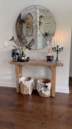 a wooden table topped with two baskets filled with halloween decorations next to a round mirror