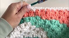 someone is crocheting an afghan with a green and orange stripe on the side